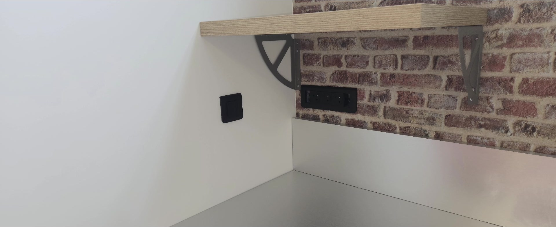 Appareillages design noir mat encastrés sur crédence brique